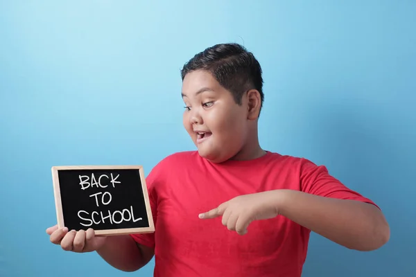 幸せな笑顔アジアの少年学生はそれに書かれた学校の単語に戻ると黒板を保持 — ストック写真
