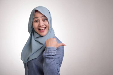 Asyalı Genç mutlu Müslüman kadın portre gülümseyen ve onun tarafında bir şey sunma işaret, kopya alanı ile