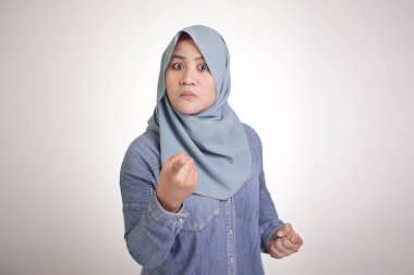 Asyalı müslüman bir kadının portresi kameraya kızgın bir ifadeyle bakıyor, uyarı veriyor, beyaz üzerine izole edilmiş.