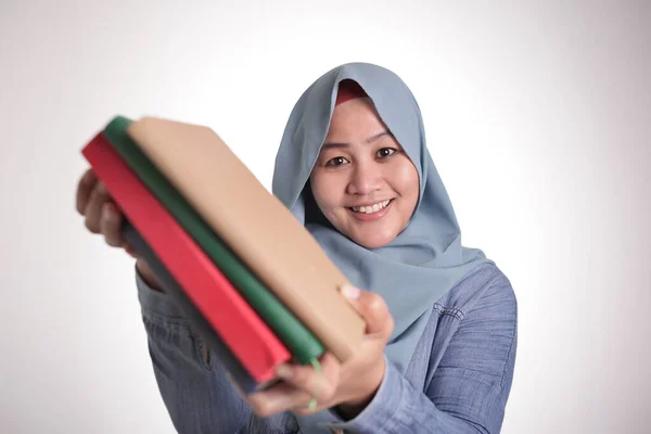 かわいい優しい笑みを浮かべてイスラム教徒女性の本を提供しているを読む肖像画 — ストック写真