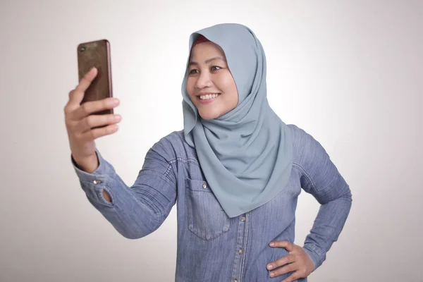 ヒジャーブを身に着けているイスラム教徒の女性の肖像写真やスマートフォンで彼女の自己の写真を撮る — ストック写真