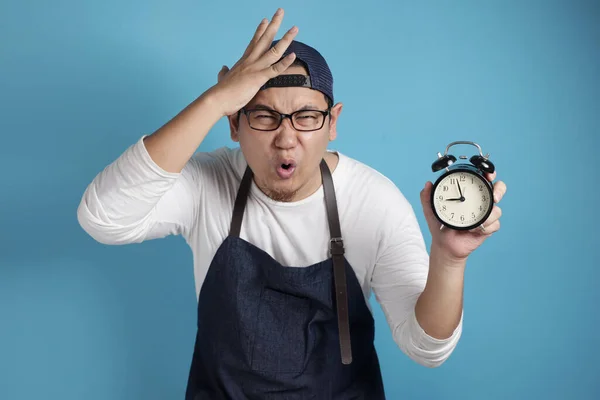 年轻有趣的亚洲男性厨师或侍者的画像 在蓝色背景下看钟表时对时间感到担忧 — 图库照片
