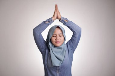 Asyalı Müslüman kadın tesettürlü kadın portresi. Yoga yapıyor, gözlerini kapatıyor ve gülümsüyor, sakin sakin, sakin bir konsept.
