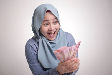 Endonezyalı Müslüman kadının portresi rupiah parası taşıyor, gülüyor ve gülüyor.
