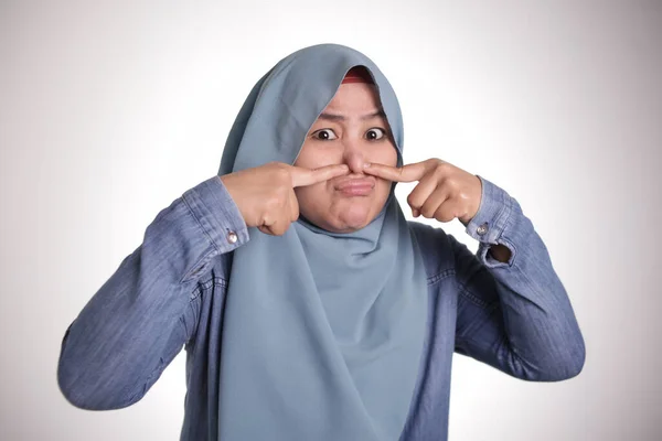 ヒジャーブを着てかわいい面白いアジア イスラム教の女性の肖像画は嫌な臭い悪臭のため彼女の鼻を閉じる — ストック写真