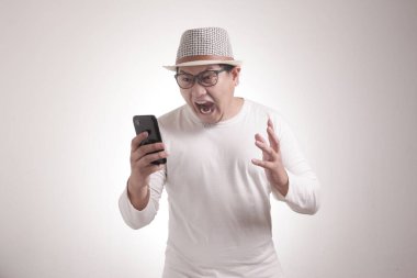 Çekici Asyalı genç adam telefonuyla konuşuyor, kötü haberler alıyor, şok olmuş kızgın bir jest yapıyor.