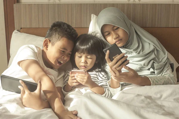 Little kids sister and brother siblings plays on gadget smart phone, phone addiction on children concept
