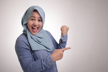 Asyalı Genç mutlu Müslüman kadın portre gülümseyen ve onun tarafında bir şey sunma işaret, kopya alanı ile