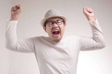 Başarılı genç Asyalı işadamının portresi zaferi kutlayarak kazanan jesti gösteriyor. Eller yukarıda kaldırdı