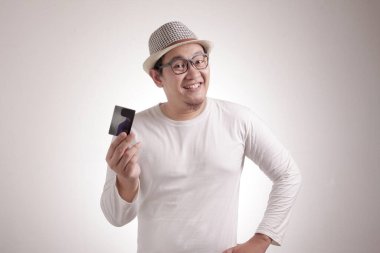 Elinde kredi kartıyla gülümseyen mutlu, şüpheci Asyalı genç bir adamın portresi.