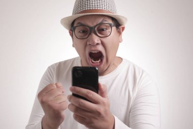 Çekici Asyalı genç adam telefonuyla konuşuyor, kötü haberler alıyor, şok olmuş kızgın bir jest yapıyor.