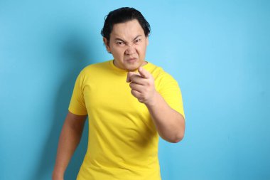 Asyalı bir adamın portresi, alaycı, mutsuz, kızgın bir yüz ifadesi gösteriyor, ileri bakıyor, uyarıda bulunuyor.