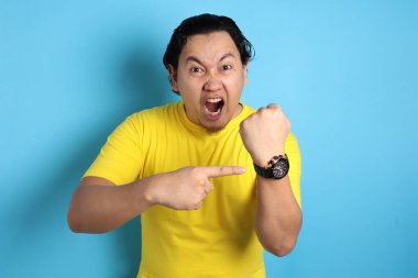 Kol saatini gösteren genç Asyalı adamın portresi, patron zaman kavramı hakkında uyarıda bulunuyor.