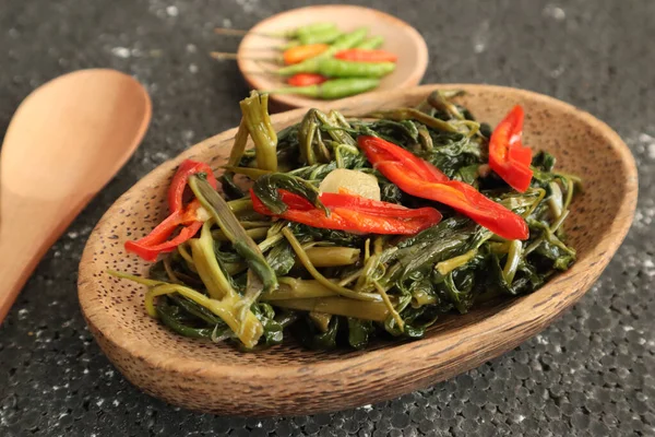 Stir fried water spinach or cah kangkung. Traditional asian indonesian food, cooked veggies, spicy vegetable dish for vegan, vegetarian meal served on wooden plate
