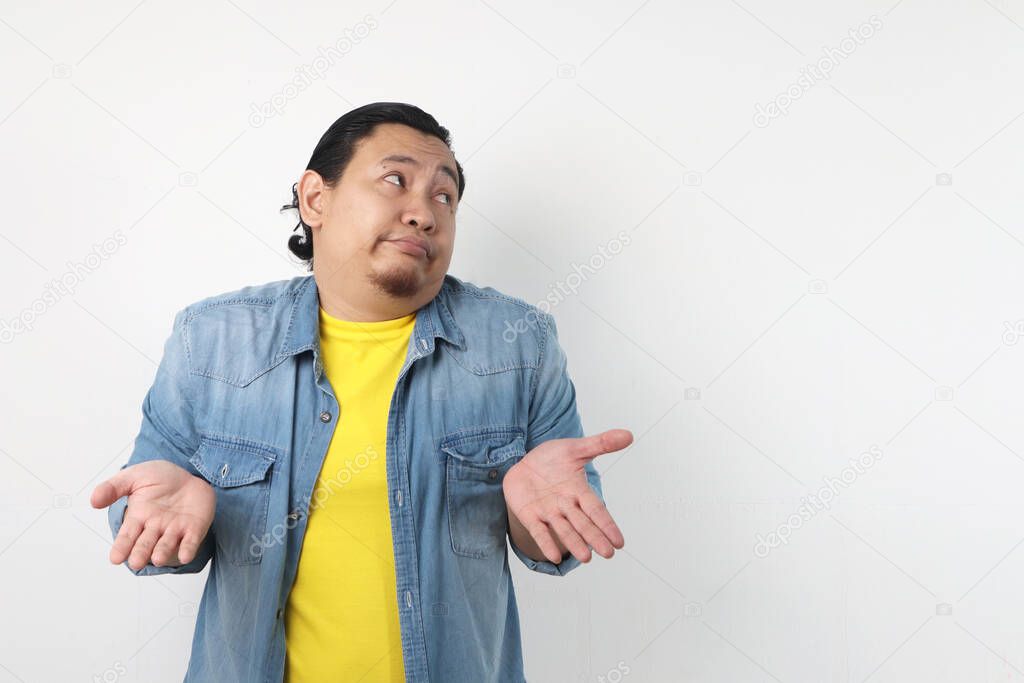 Photo image of funny Asian man with shrug shoulder up gesture, showing i don't know or rejection