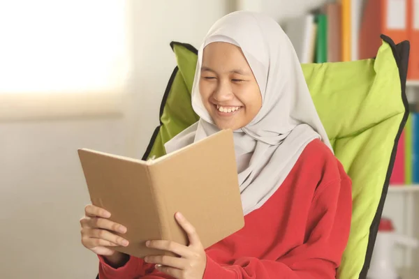 Szczęśliwa Azjatycka Muzułmanka Hidżabie Uśmiechnięta Podczas Czytania Książki Zajęcia Rekreacyjne — Zdjęcie stockowe