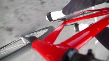 Adam sabit dişli kırmızı bir bisiklete biniyor.