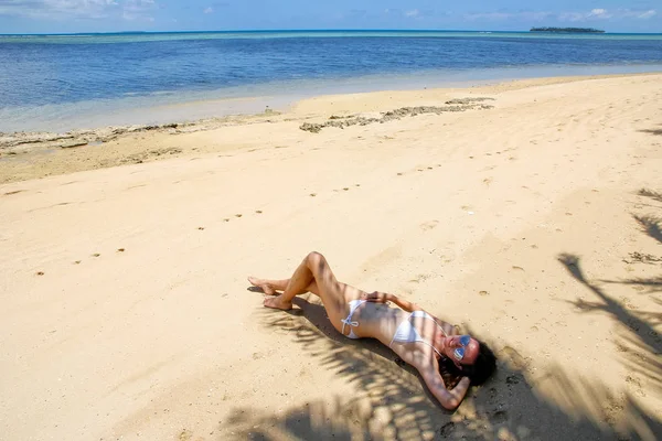 Молодая женщина в бикини лежит на пляже на острове Макахаа недалеко — стоковое фото