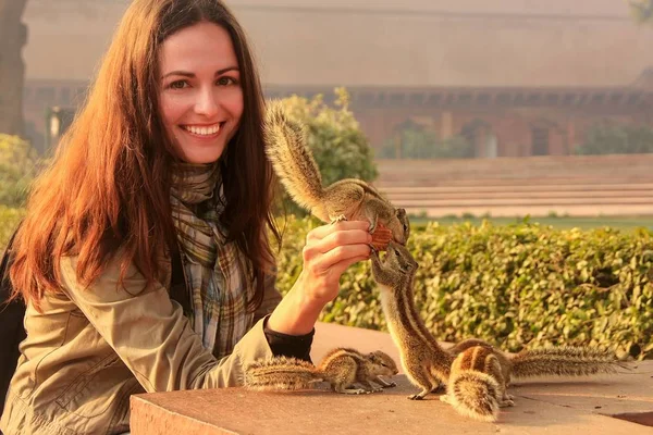 Giovane donna che nutre scoiattoli di palma indiani ad Agra Fort, Uttar Pradesh, India — Foto Stock
