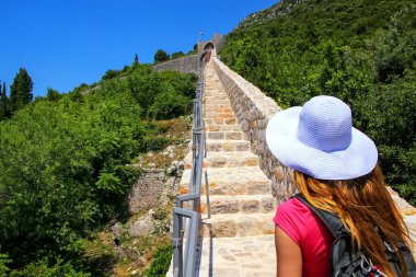 Ston kentindeki Peljesac savunma duvarı üzerinde yürüyen genç kadın