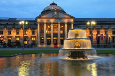 WIESBADEN, GERMANY-MAY 24: Kurhaus and Bowling Green in the evening with lights on May 24, 2017 in Wiesbaden, Hesse, Germany. Wiesbaden is one of the oldest spa towns in Europe clipart