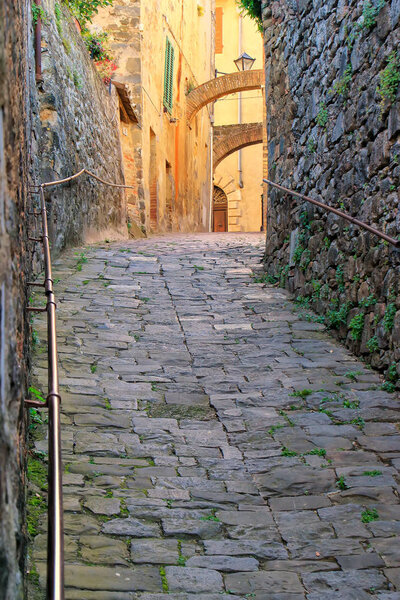 Narrow street in historic center of Montalcino town, Val d'Orcia, Tuscany, Italy. The town takes its name from a variety of oak tree that once covered the terrain.