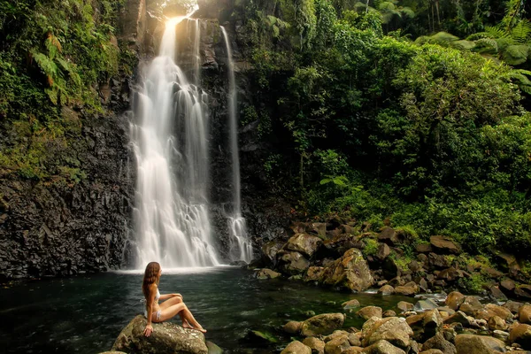 Junge Frau im Bikini sitzt an der Mitte tavoro Wasserfälle in bou — Stockfoto