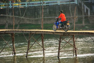Vang Vieng, Laos - Kasım 25: Kimliği belirsiz üzerinde 25 Kasım 2011 yılında Vang Vieng, Laos köprüde motosiklet sürmek. Vang Vieng bir turist odaklı Vientiane ili yeridir.