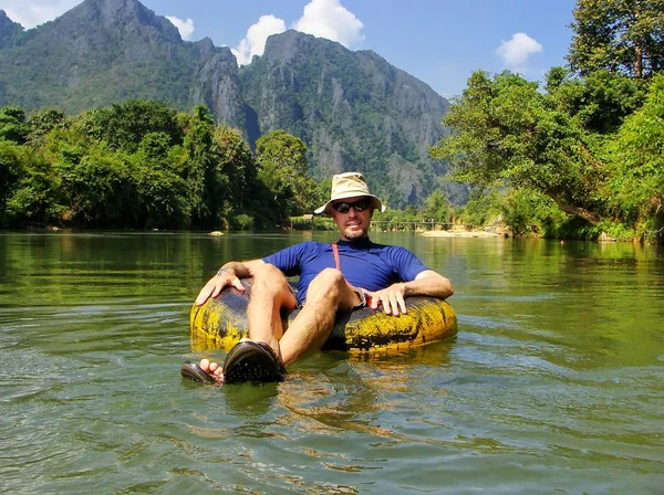 Turista descendo Nam Song River em um tubo cercado por carste — Fotografia de Stock