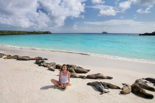 Ung kvinna sitter med en grupp av Galapagos sjölejon på Gardn — Stockfoto