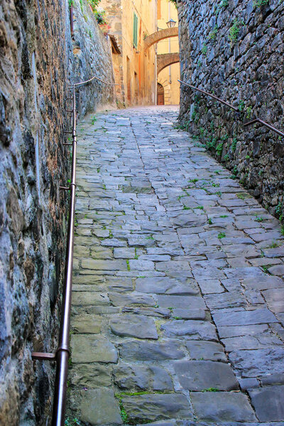 Narrow street in historic center of Montalcino town, Val d'Orcia, Tuscany, Italy. The town takes its name from a variety of oak tree that once covered the terrain.