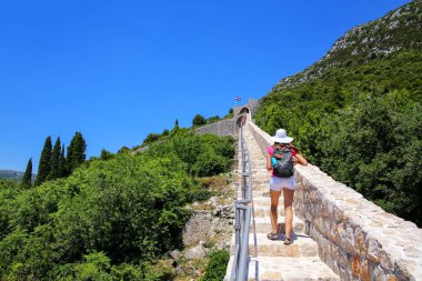 Hırvatistan 'ın Peljesac Yarımadası' ndaki Ston kasabasının savunma duvarında yürüyen genç bir kadın. Ston Ragusan Cumhuriyeti 'nin büyük bir kalesiydi.