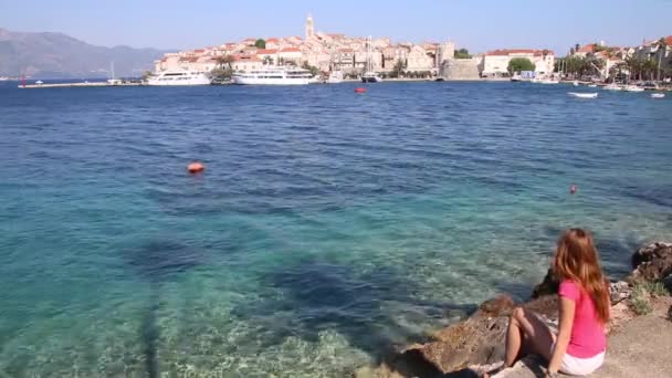 坐在克罗地亚Korcula镇海滨的年轻妇女 科库拉是科库拉岛受保护的东海岸的一个历史性的设防城镇 — 图库视频影像