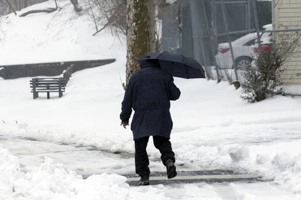 Mann läuft bei Schneesturm mit Regenschirm — Stockfoto