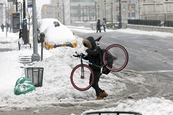 Mężczyzna niesie ze sobą rower podczas przekraczania ulicy w burzy śnieżnej — Zdjęcie stockowe