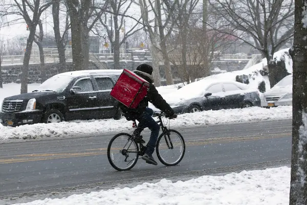 Persona haciendo entrega en bicicleta durante tormenta de nieve — Foto de Stock