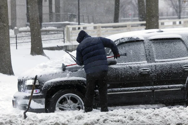 Adam araba fırça ile kar fırtınası sırasında temizler. — Stok fotoğraf