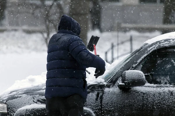 Man cleans car with brush during snow storm — Stock Photo, Image