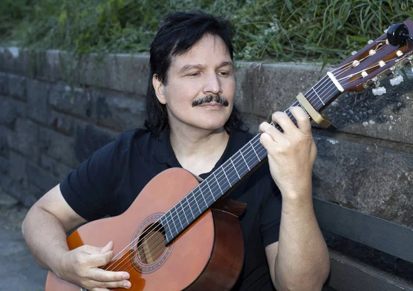 Латиноамериканец играет на акустической гитаре на открытом воздухе — стоковое фото