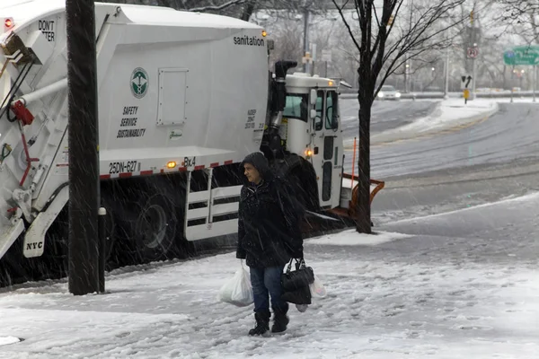Woman passes by parked snow removal vehicle during storm in the — Stock Photo, Image