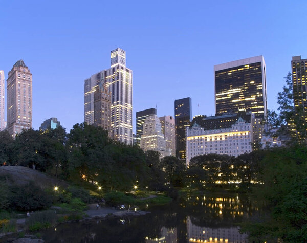 Central Park pond and surrouding architecture at twilight in New York City.