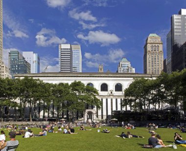 NEW YORK, NEW YORK / USA - 9 Haziran 2018: İnsanlar güneşli bir günde Bryant Park 'ın çimlerinde dinleniyor. 