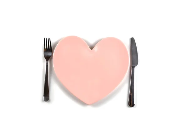 Placa en forma de corazón, cuchillo de mesa y tenedor sobre fondo blanco — Foto de Stock