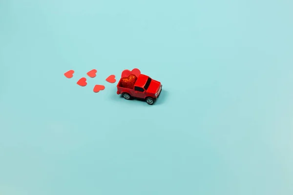 Concepto del Día de San Valentín. Coche de juguete rojo miniatura con corazones rojos — Foto de Stock