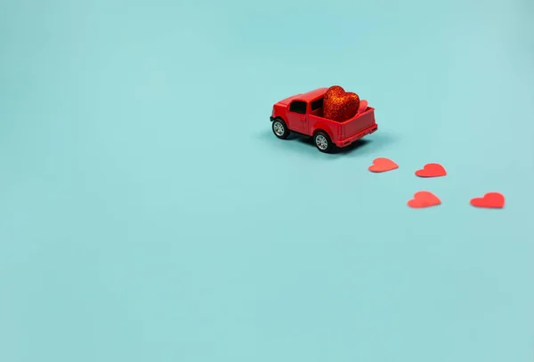 Concepto del Día de San Valentín. Coche de juguete rojo miniatura con corazones rojos — Foto de Stock