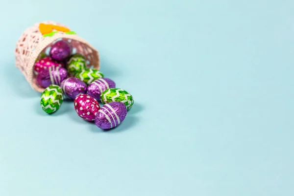 Huevos de Pascua de chocolate coloridos en fondo azul cesta. Los huevos pequeños de chocolate en la laminilla. Dulce de Pascua tradicional. Copiar espacio — Foto de Stock