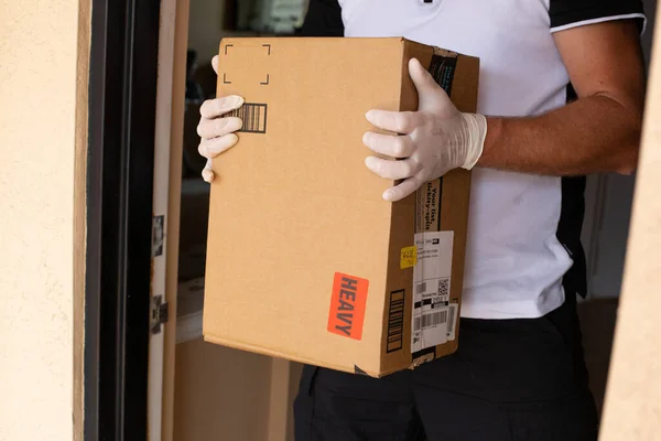 Amazon Prime paquete en las manos en la puerta del apartamento. Cuarentena debida al Coronavirus. Amazon es una empresa en línea y es el mayor minorista del mundo . — Foto de Stock
