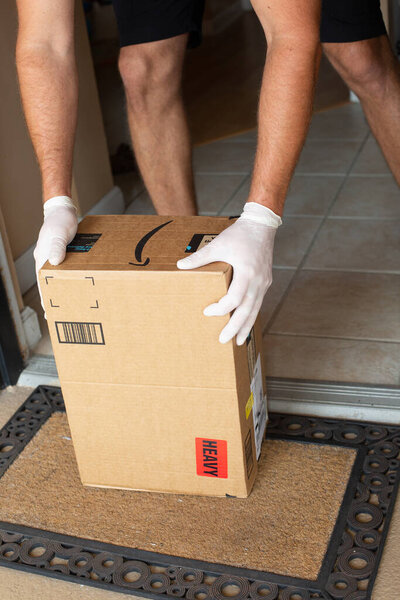 Amazon Prime package in hands in at apartment door. Quarantine due Coronavirus. Amazon is an online company and is the largest retailer in the world.