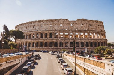 ROME, ITALY - 10 MARCH 2018: ancient Colosseum ruins on sunny day with cars parked on street clipart