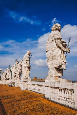 statues on top of St Peters Basilica on blue sky, Vatican city, Italy clipart